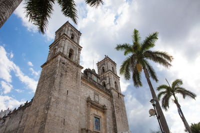 Low angle view of church by palm trees against sky