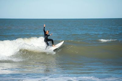 Man surfing in sea against sky