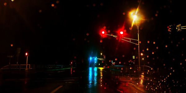 Illuminated street lights on road during rainy season at night