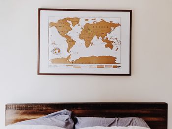 Bed against world map on wall at home