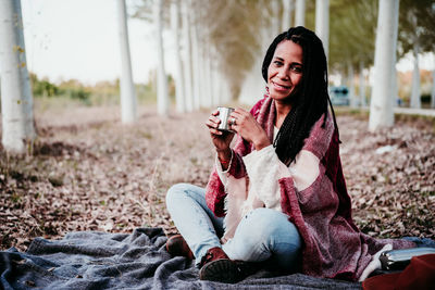 Beautiful young woman drinking water from while sitting outdoors