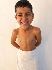 Portrait of smiling boy standing against white wall