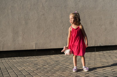 Portrait of young woman standing against wall