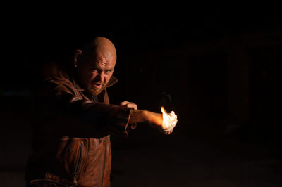Man holding fire against black background