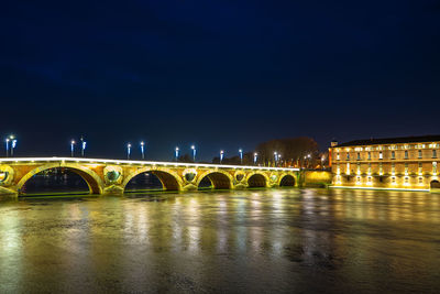 Illuminated bridge over river at night