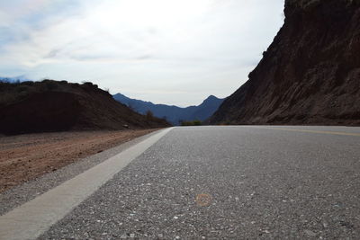 Surface level of road amidst mountains against sky