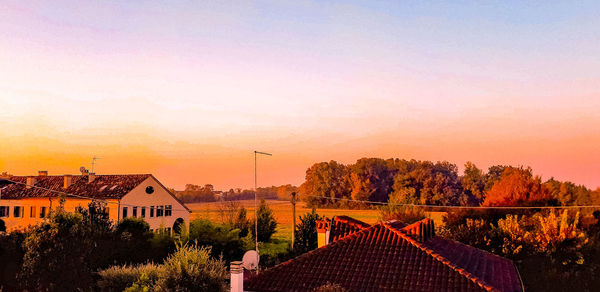 Houses and trees against sky during sunset