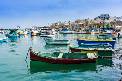 Boats moored at harbor against clear sky