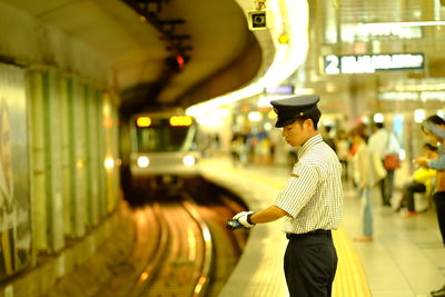 Rear view of woman standing at railroad station