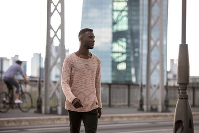 Young man looking away while walking on road