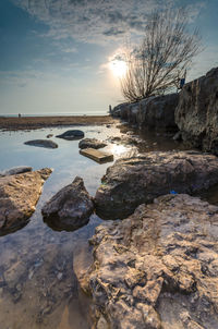 Rocks in sea against sky during sunset