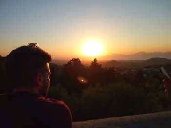 Boy in park against sky during sunset