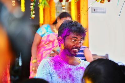 Portrait of smiling man with multi colored people in background