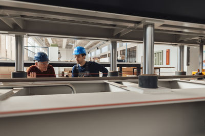 Businessman having discussion over machinery with colleague