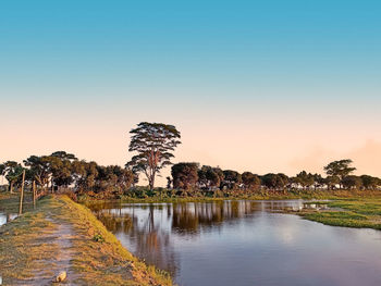 Scenic view of lake against clear sky at sunset