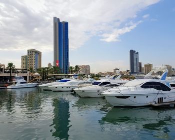 Boats moored in city by buildings against sky