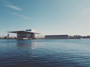 Buildings by sea against clear blue sky