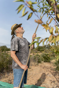 Portrait of a male farmer harvesting almonds by hand.