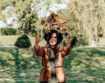 Front view of young woman throwing autumn leaves in air. fall colors, happy, positive emotion.