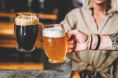 Midsection of woman drinking beer in glass