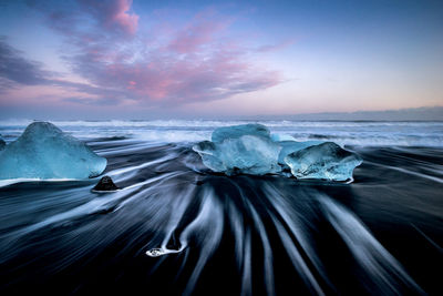 Long exposure of waves in sea against sky during sunset