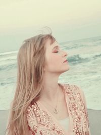 Beautiful woman with closed eyes against sea