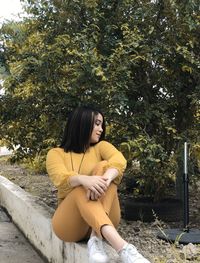 Full length of woman sitting on retaining wall