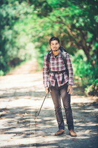 Portrait of male hiker standing on road in forest