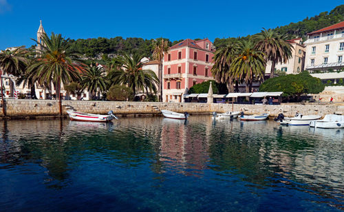 Boats moored in canal by buildings against clear sky