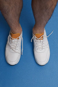 Low section of man standing on blue floor