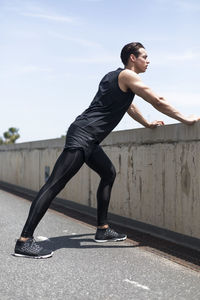 Full length of young woman exercising on road