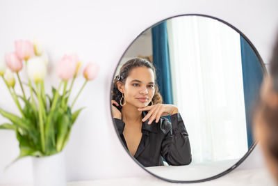 Portrait of young woman looking through window