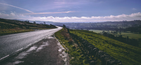 Scenic view of road amidst field against sky