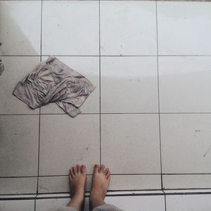 Low section of woman standing by fabric on tiled floor