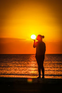 Silhouette man looking at sea against sky during sunset