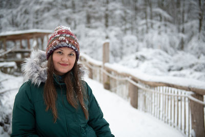 Portrait of young woman standing on snow covered field