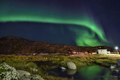 Scenic view of illuminated building by mountain against sky at night