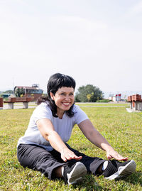 Portrait of smiling young woman sitting on land