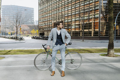 Male entrepreneur with bicycle standing in city looking away