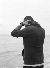 Rear view of man standing by sea against sky