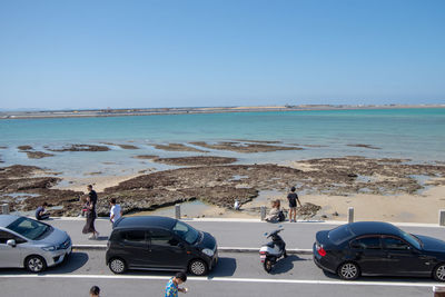 People on beach against clear blue sky