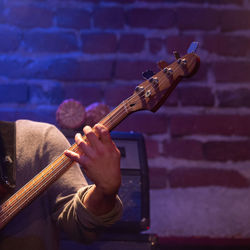 Midsection of man playing guitar against the wall