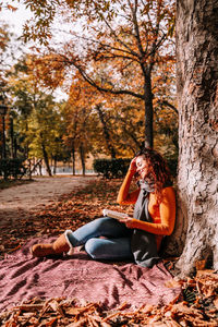 Portrait of a young woman sitting in park during autumn