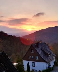 Houses and buildings against sky during sunset