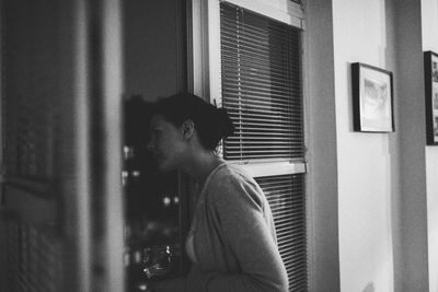 Woman looking through window at home