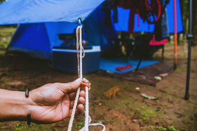 Cropped hand of man holding tent rope