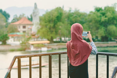 Rear view of man photographing railing