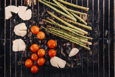 Directly above shot of cherry tomato, feta cheese and asparagus on barbecue grill