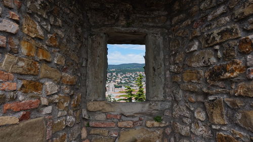 View of old ruin building against sky seen through window