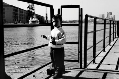 Full length of woman standing on railing against river